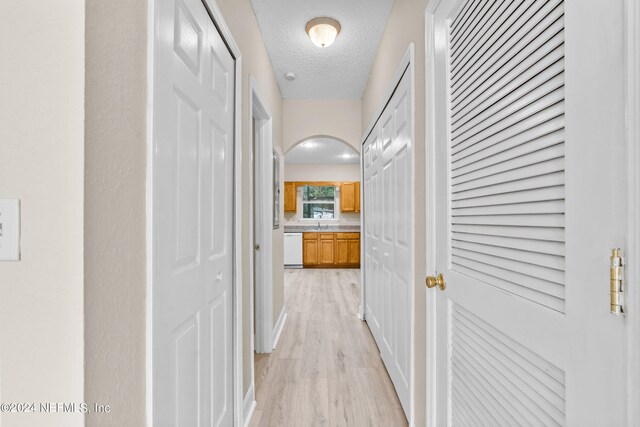 hall with a textured ceiling and light hardwood / wood-style flooring