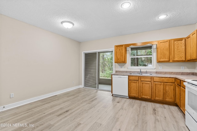 kitchen with white appliances, a textured ceiling, light hardwood / wood-style flooring, and sink