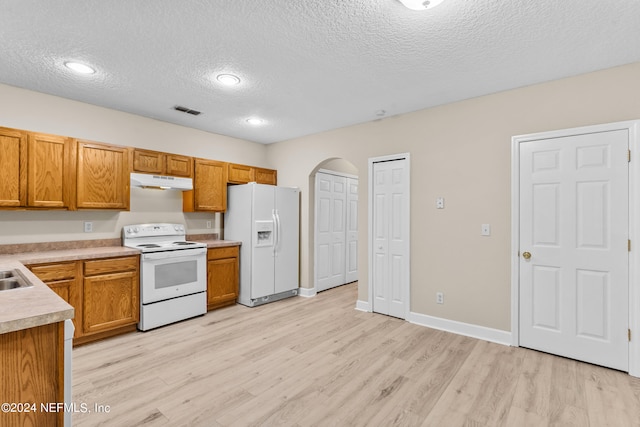 kitchen with light hardwood / wood-style floors, a textured ceiling, and white appliances