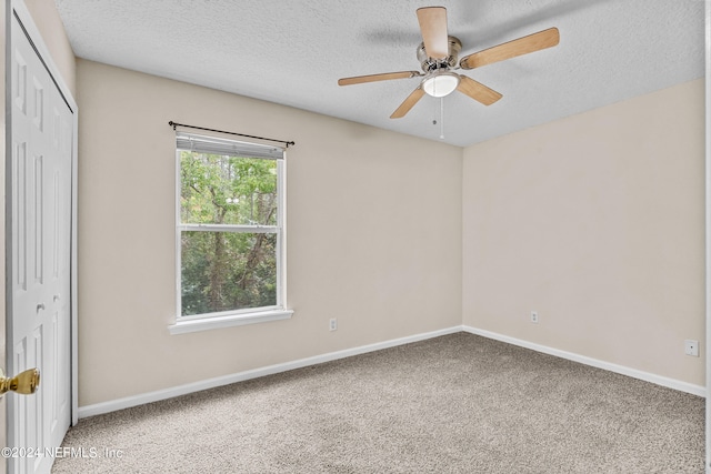 empty room featuring ceiling fan, carpet flooring, and a textured ceiling