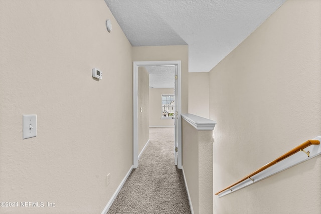 corridor featuring a textured ceiling and light colored carpet