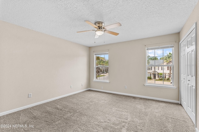 unfurnished bedroom with multiple windows, carpet, and ceiling fan