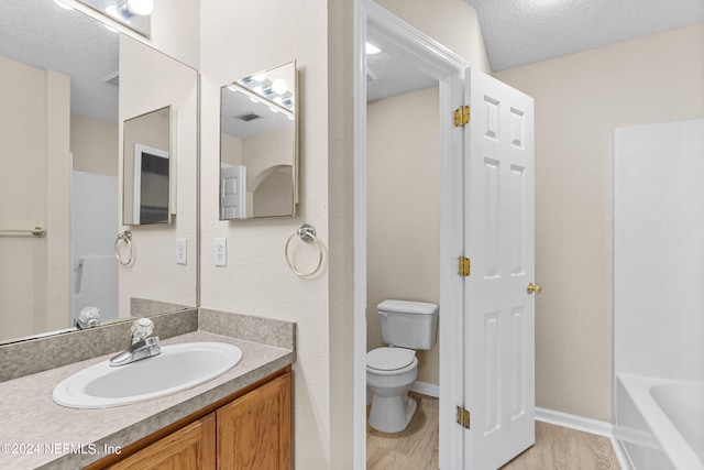 bathroom featuring vanity, toilet, hardwood / wood-style flooring, and a textured ceiling