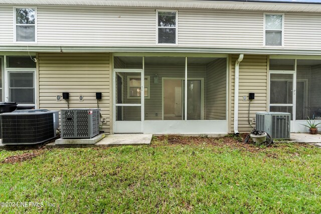 rear view of property with central AC, a yard, and a sunroom