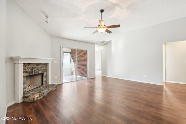 unfurnished living room with ceiling fan, a stone fireplace, dark hardwood / wood-style floors, and a textured ceiling