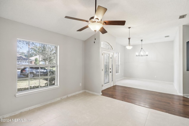 interior space with vaulted ceiling, ceiling fan with notable chandelier, and light tile patterned floors