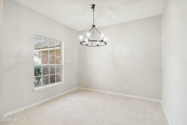 unfurnished room with a notable chandelier