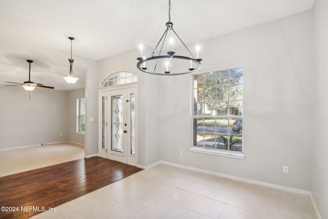 tiled foyer featuring ceiling fan with notable chandelier and a healthy amount of sunlight