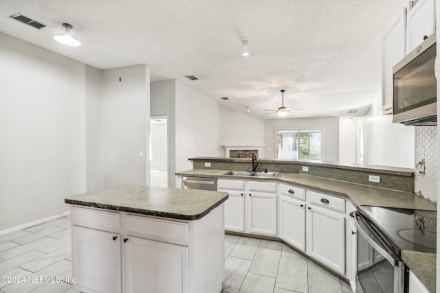 kitchen with appliances with stainless steel finishes, sink, a kitchen island, and white cabinets