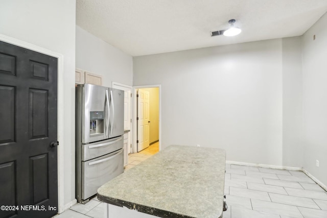 kitchen with stainless steel fridge and light brown cabinetry