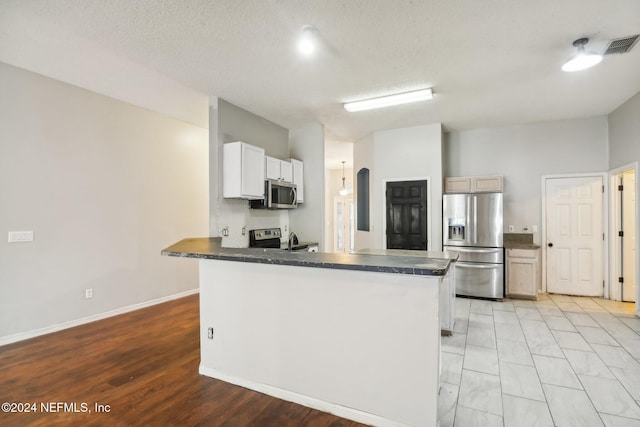 kitchen with white cabinetry, appliances with stainless steel finishes, kitchen peninsula, and a textured ceiling