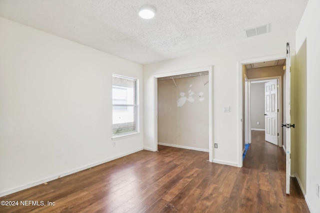 unfurnished bedroom featuring dark wood-type flooring, a closet, and a textured ceiling