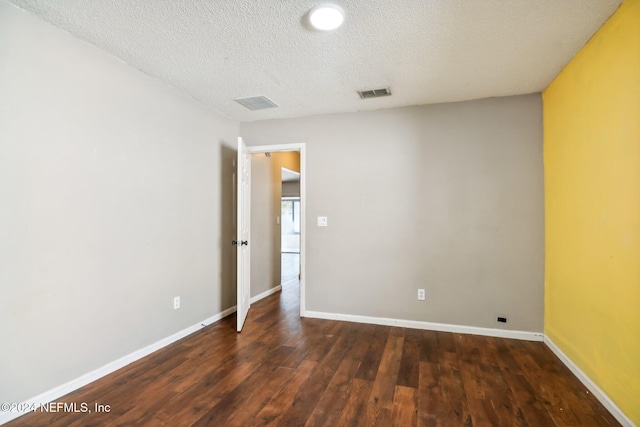 empty room with dark hardwood / wood-style floors and a textured ceiling