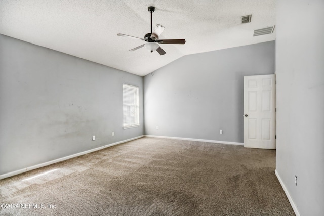 spare room with a textured ceiling, vaulted ceiling, ceiling fan, and carpet