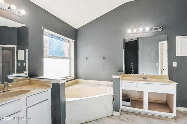 bathroom with lofted ceiling, vanity, and a tub