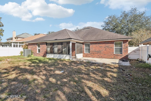 back of house featuring a sunroom, a lawn, central air condition unit, and a patio area