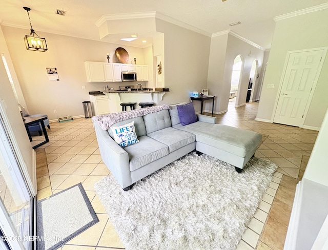 living room with an inviting chandelier, light tile patterned flooring, and ornamental molding