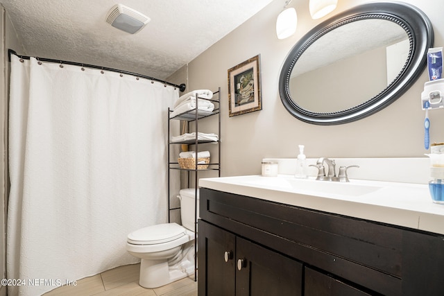 bathroom featuring vanity, a textured ceiling, and toilet