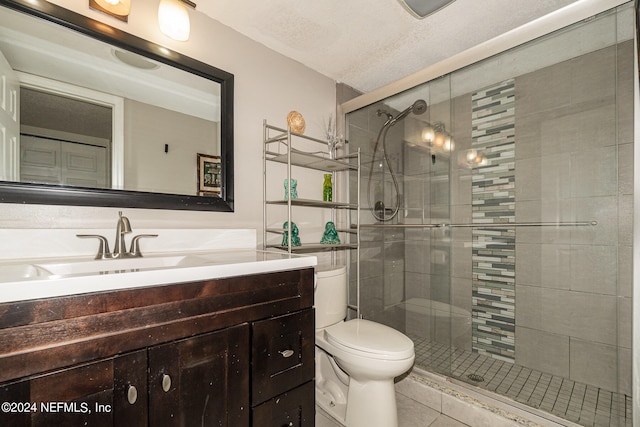 bathroom featuring a shower with door, vanity, toilet, and tile patterned floors