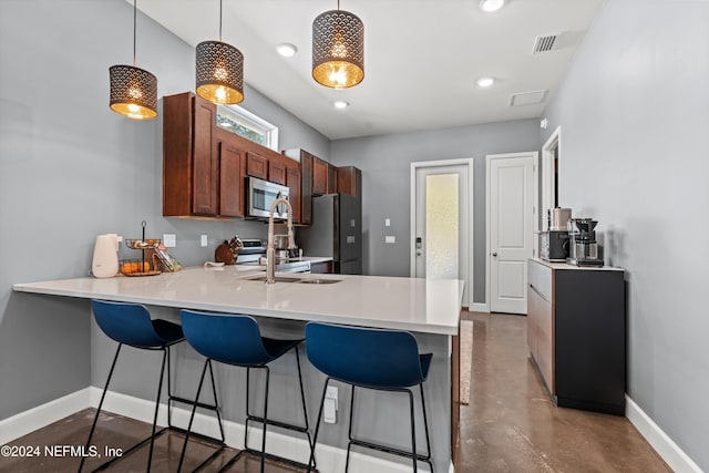 kitchen featuring kitchen peninsula, stainless steel appliances, sink, concrete flooring, and pendant lighting