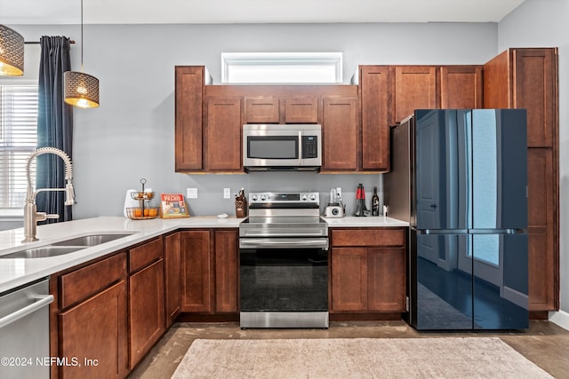 kitchen featuring concrete floors, decorative light fixtures, stainless steel appliances, and sink