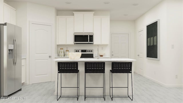 kitchen with appliances with stainless steel finishes, white cabinetry, a kitchen island with sink, and light wood-type flooring