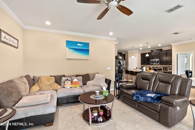 tiled living room featuring ceiling fan, ornamental molding, and a textured ceiling