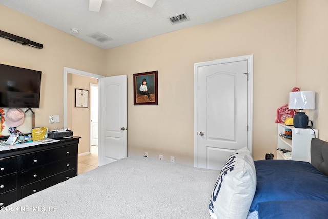 bedroom featuring a textured ceiling, light colored carpet, and ceiling fan