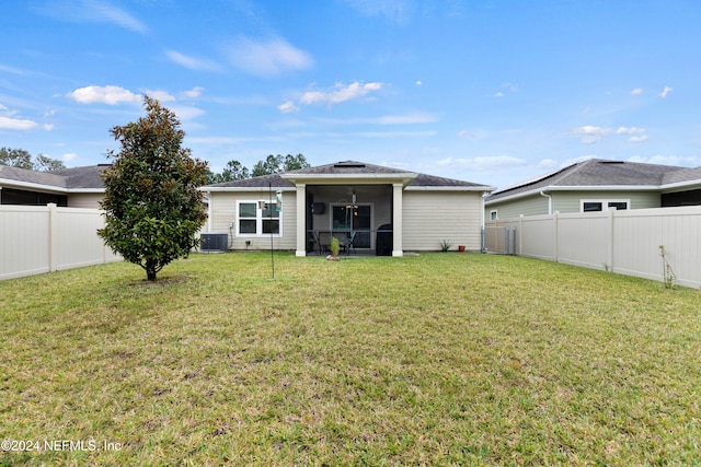 rear view of property featuring cooling unit, a sunroom, and a lawn