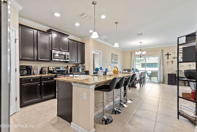 kitchen with an island with sink, light stone countertops, a kitchen bar, pendant lighting, and stainless steel appliances