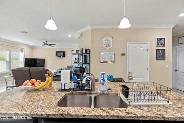 kitchen featuring hanging light fixtures, ornamental molding, sink, light stone countertops, and ceiling fan