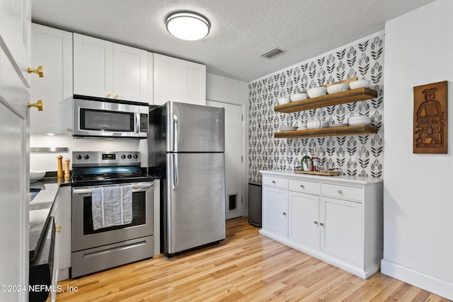 kitchen featuring white cabinetry, light hardwood / wood-style floors, stainless steel appliances, and a textured ceiling