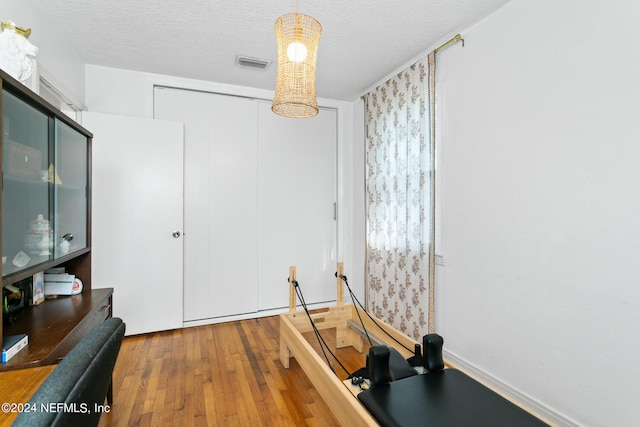 workout area with a textured ceiling and wood-type flooring