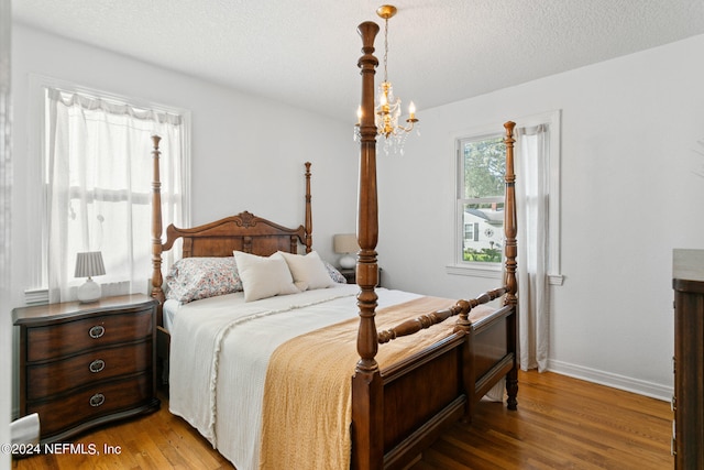 bedroom featuring a notable chandelier, hardwood / wood-style floors, and a textured ceiling