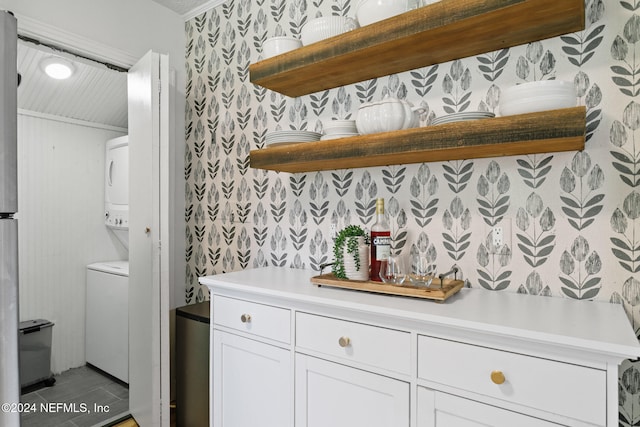 bar with white cabinetry and stacked washer and dryer