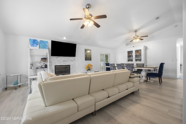 living room with ceiling fan, a fireplace, light hardwood / wood-style floors, and lofted ceiling