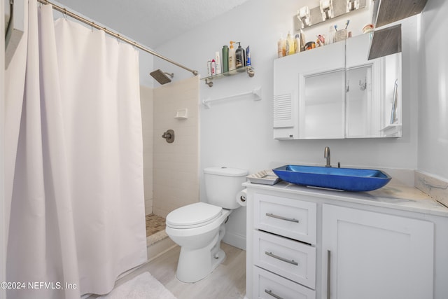 bathroom with wood-type flooring, a textured ceiling, toilet, vanity, and a shower with shower curtain