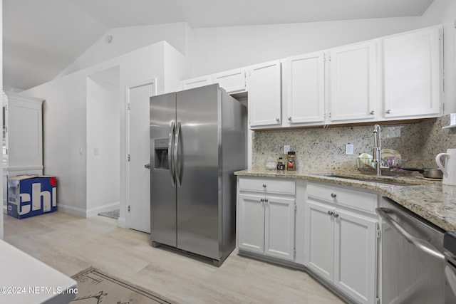 kitchen with tasteful backsplash, stainless steel appliances, sink, white cabinetry, and lofted ceiling