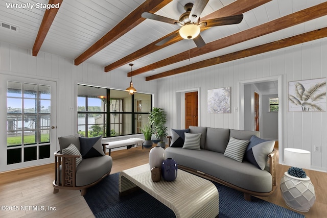 living area featuring visible vents, wood walls, beam ceiling, ceiling fan, and light wood finished floors