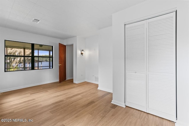 interior space featuring a closet, baseboards, visible vents, and light wood-style floors