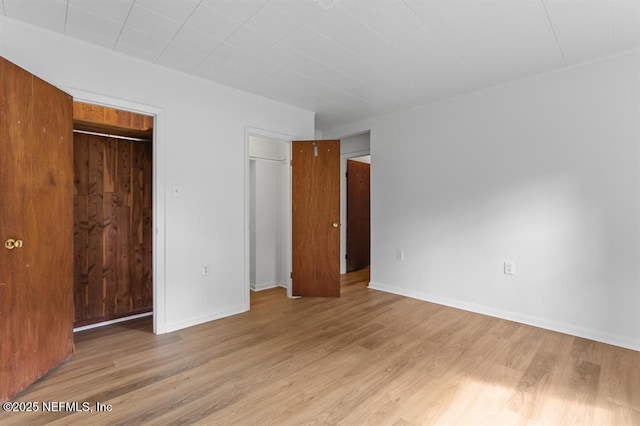unfurnished bedroom with baseboards, light wood finished floors, and a closet
