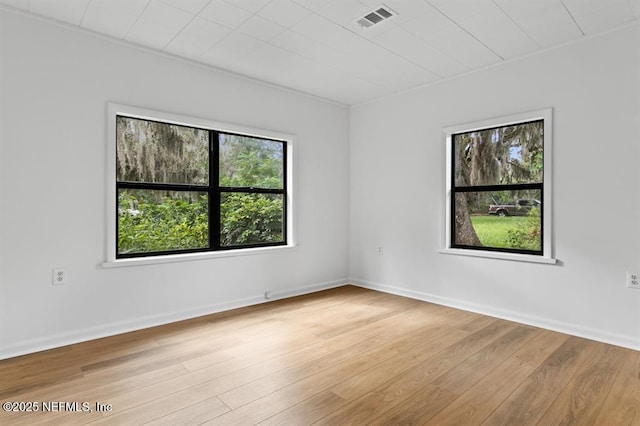 spare room featuring baseboards, light wood-style flooring, and visible vents