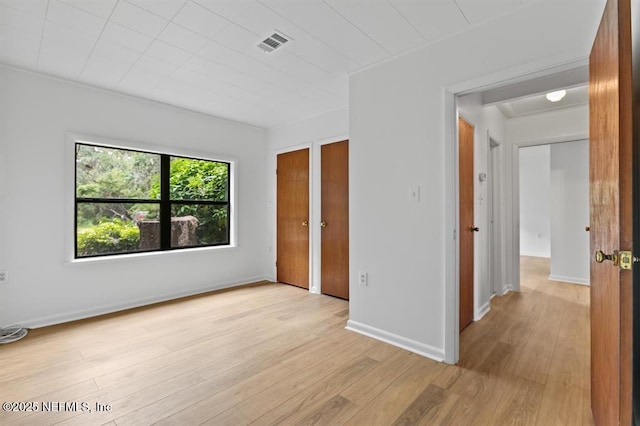 unfurnished bedroom with light wood-style floors, baseboards, and visible vents