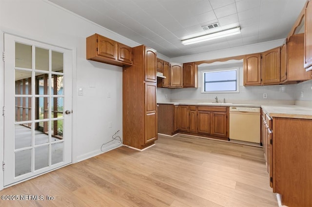 kitchen featuring visible vents, white dishwasher, a sink, and brown cabinets