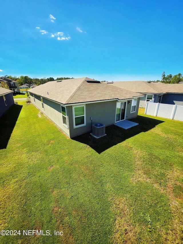 rear view of property featuring central air condition unit and a yard