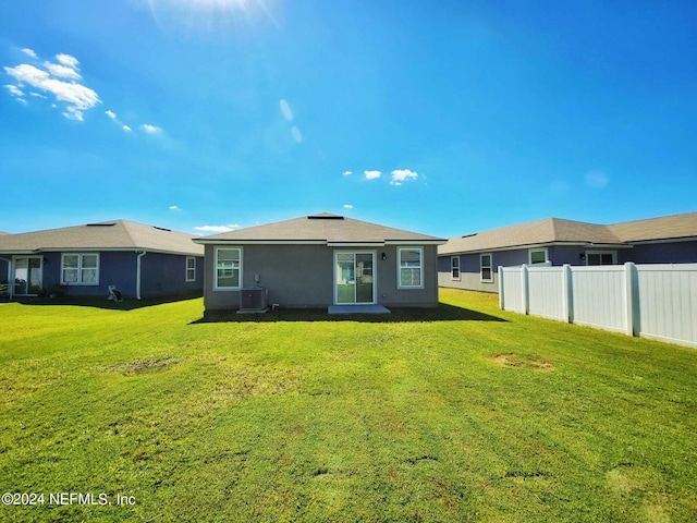 rear view of property with central AC and a lawn