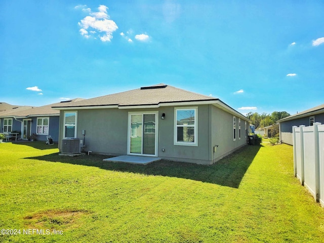 rear view of house featuring cooling unit and a lawn