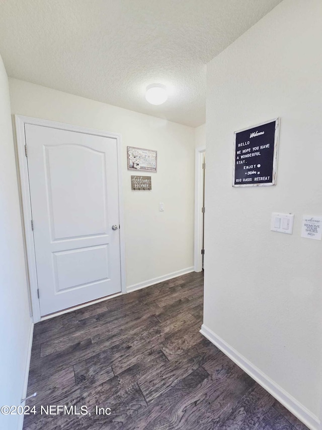 corridor featuring a textured ceiling and dark hardwood / wood-style flooring