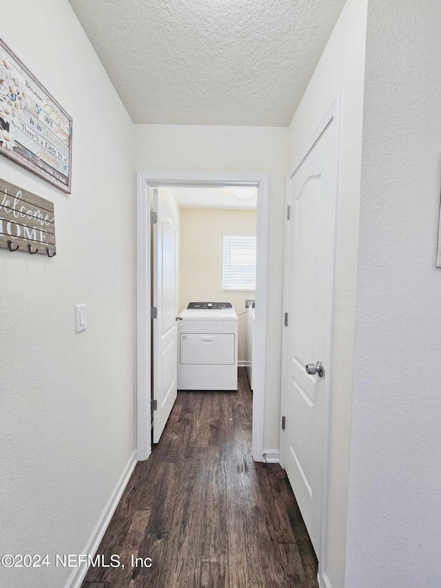 hallway with a textured ceiling, washing machine and dryer, and dark hardwood / wood-style floors