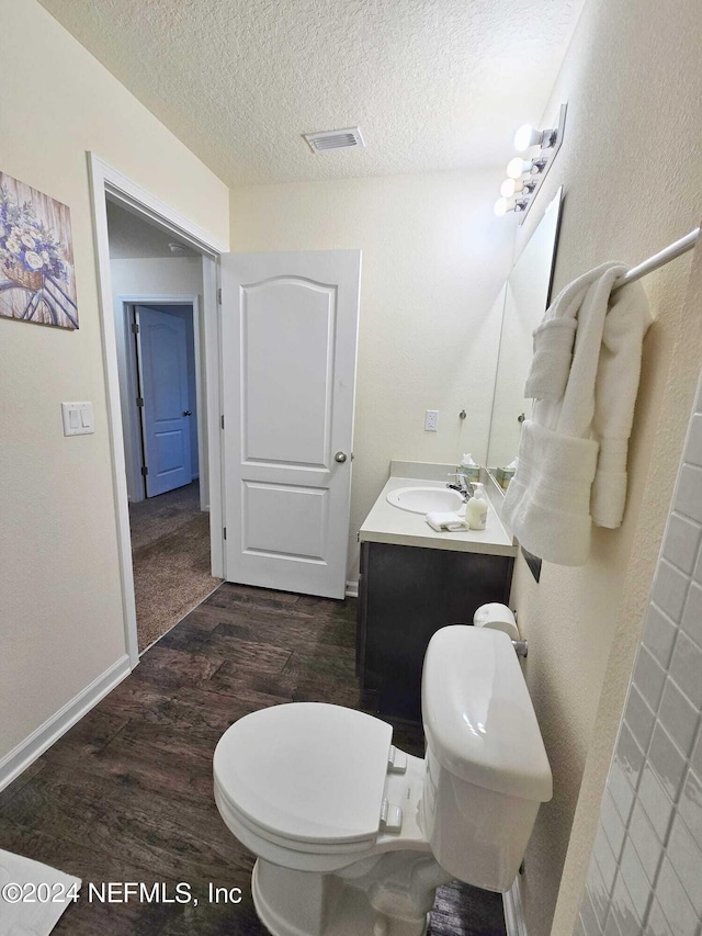 bathroom featuring toilet, a textured ceiling, vanity, and wood-type flooring